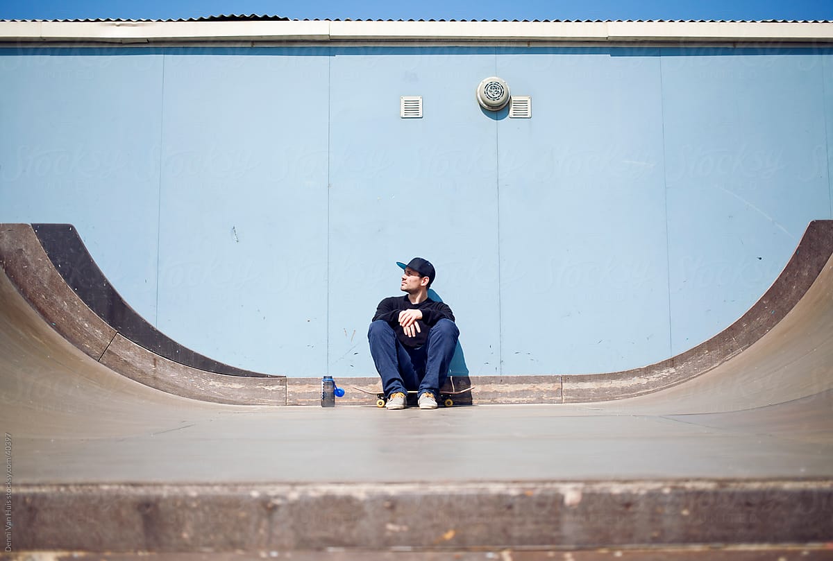 Young man sitting down to take a break from skateboarding