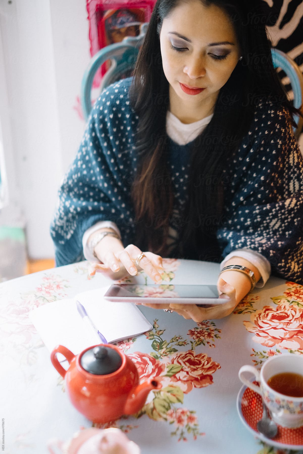Brunette Asiatic Using a Digital Tablet while drinking a Cup of Tea