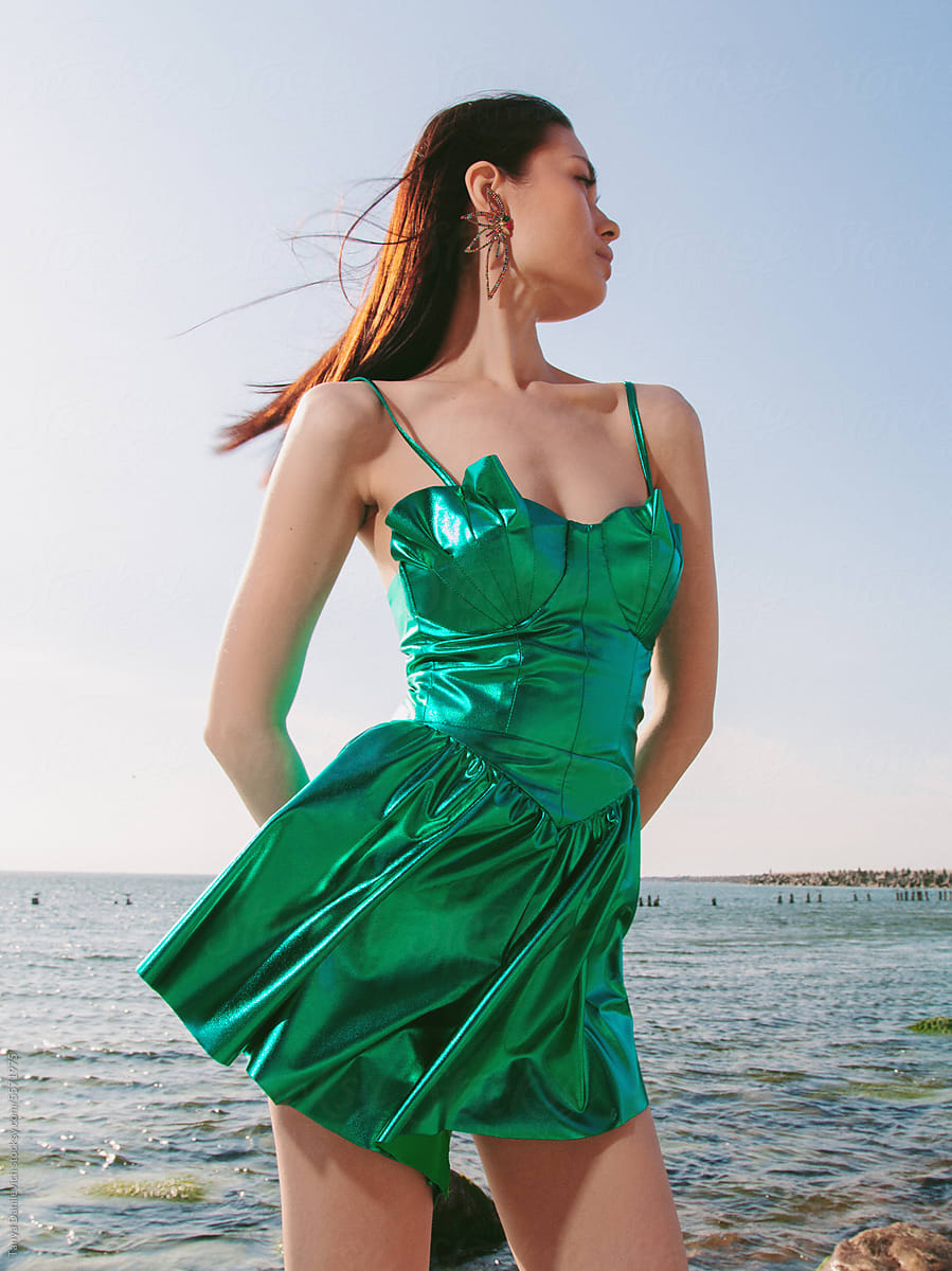 A portrait of a girl in a green dress on the sea background.