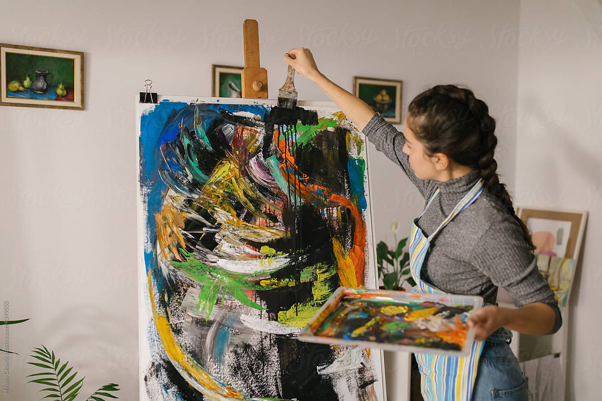 Female art student painting on canvas in home studio