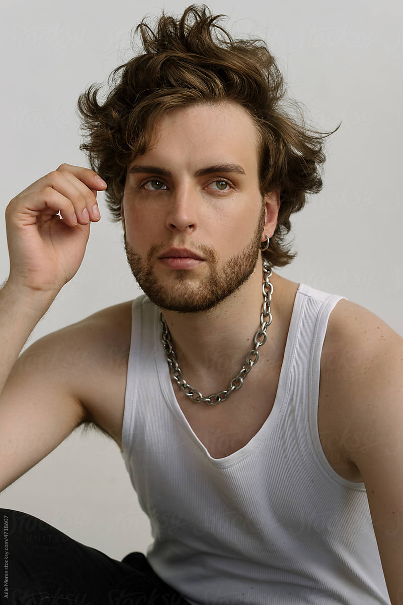 Attractive bearded guy with messy hair in a white shirt and chain