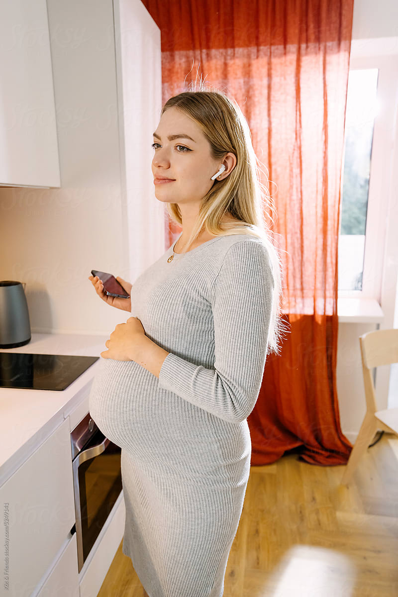 Pregnant Woman Listening To A Podcast In Headphones At Home