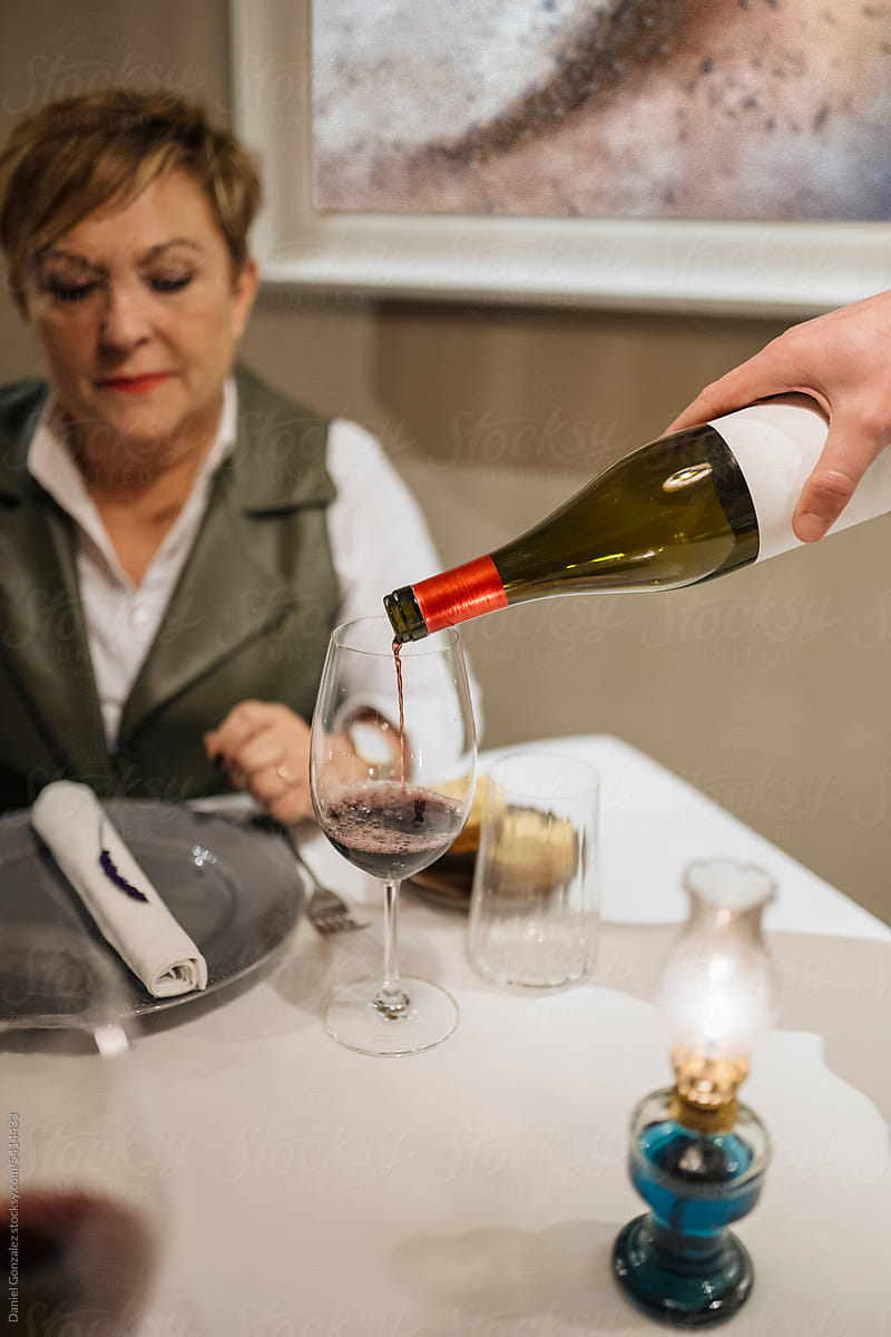 Middle aged woman sitting at table and waiting for wine