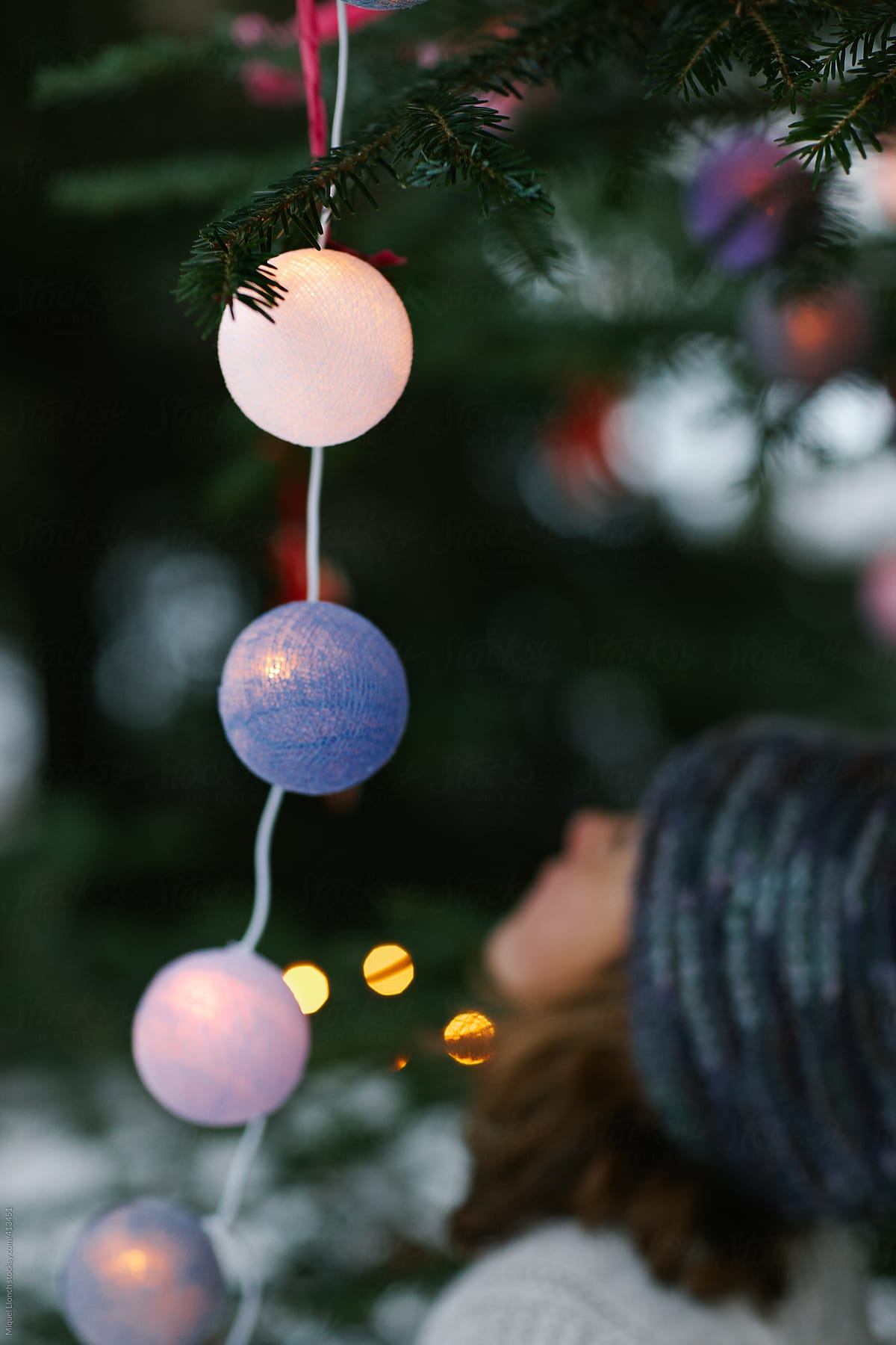 Little child and Christmas tree lit balls