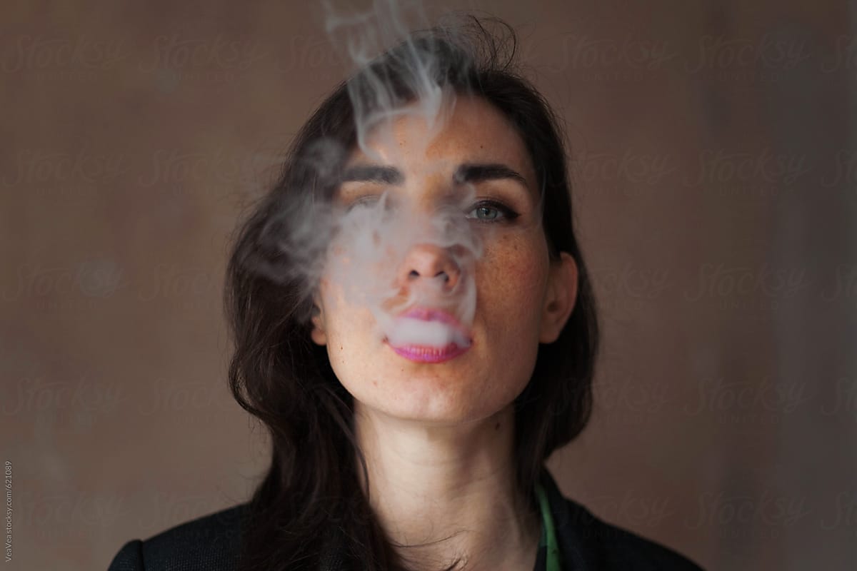Portrait of a young woman blowing a cigarette smoke