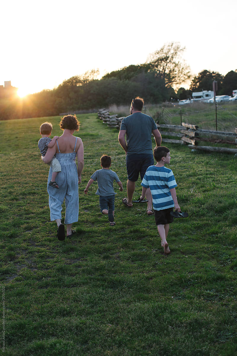 Family walking in grass at sunset