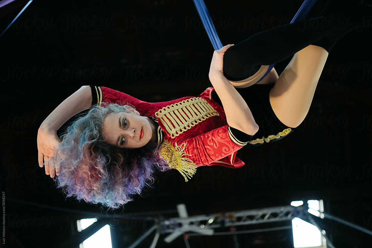 Circus Woman Performer With Red Uniform Doing Acrobatics In The Air.