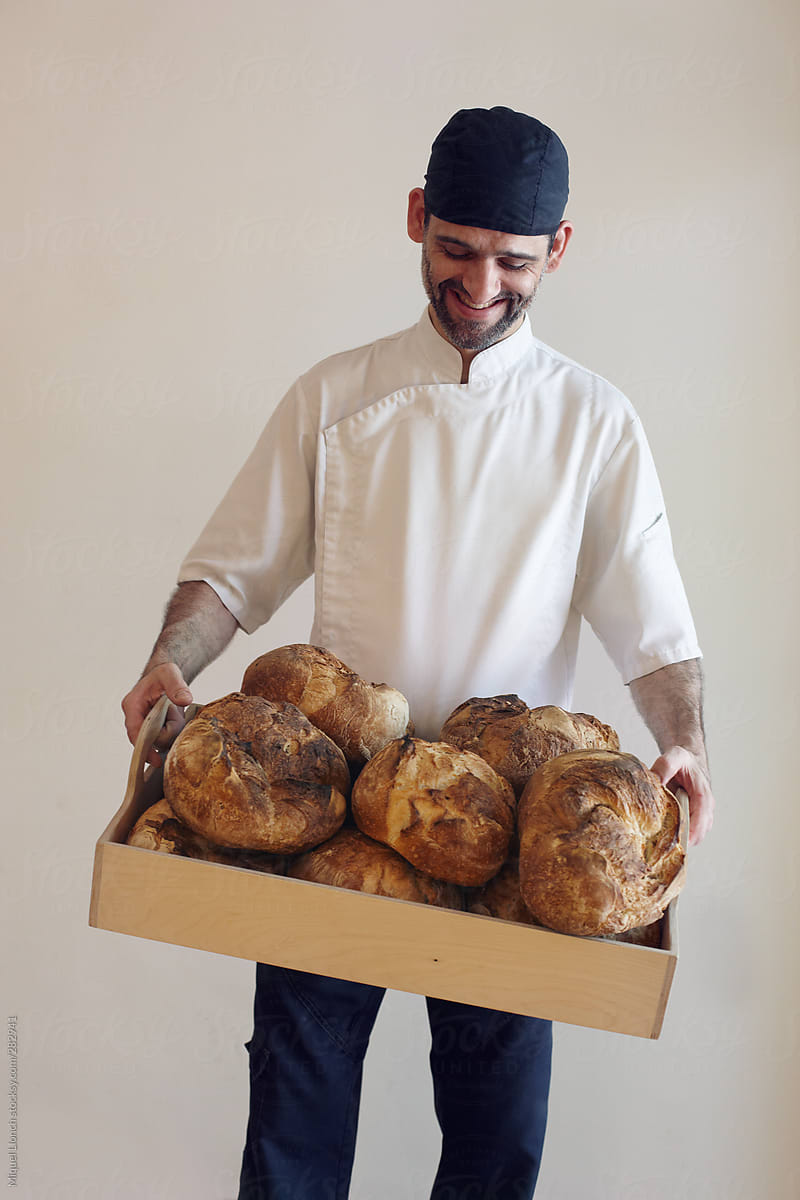 Artisan baker holding a tray full of bread loaves