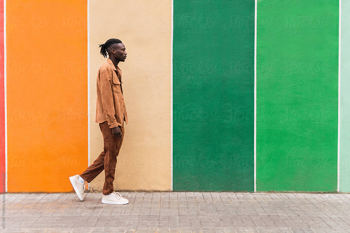 Black man walking along multicolored wall