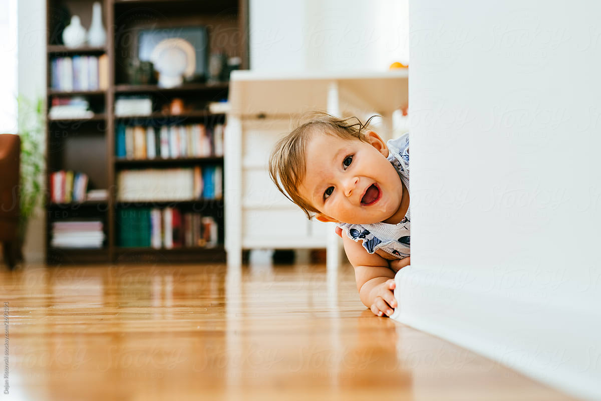 Baby crawling on the floor and playing peek a boo