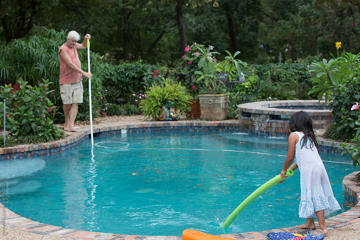 Grandfather and granddaughter cleaning a swimming pool