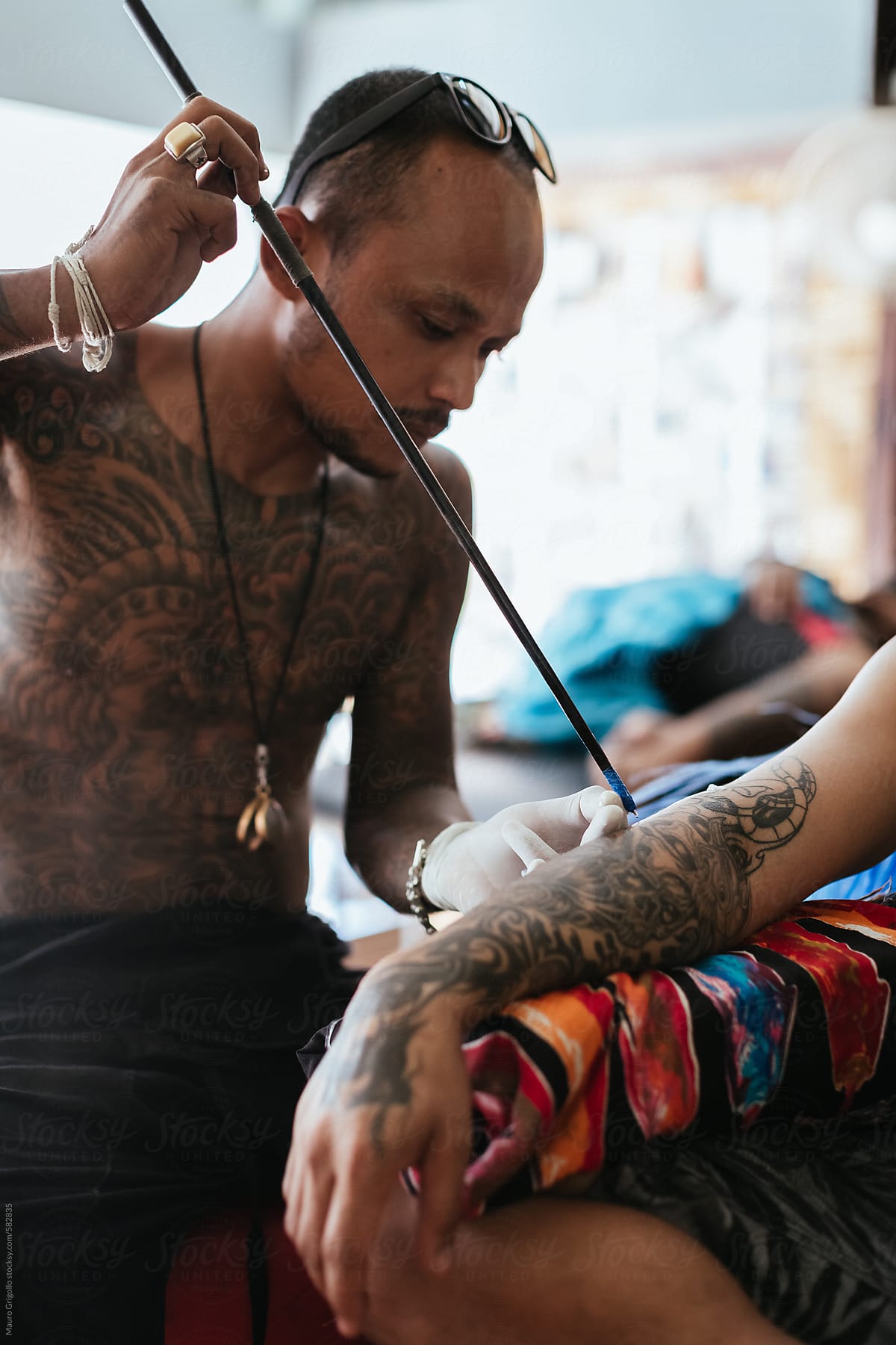 Thai tattoo artist working on a tattoo inside his studio