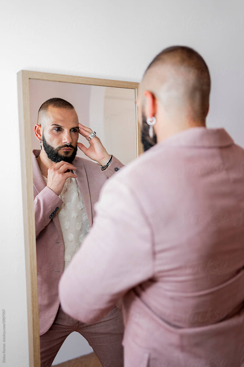 Beautiful man with makeup looking at mirror