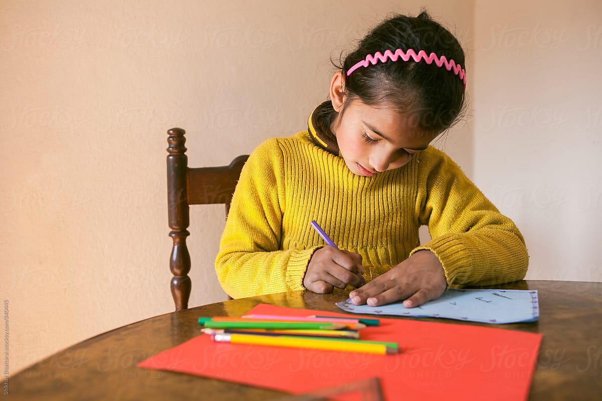 A young child sitting on a desk and making holiday cards.