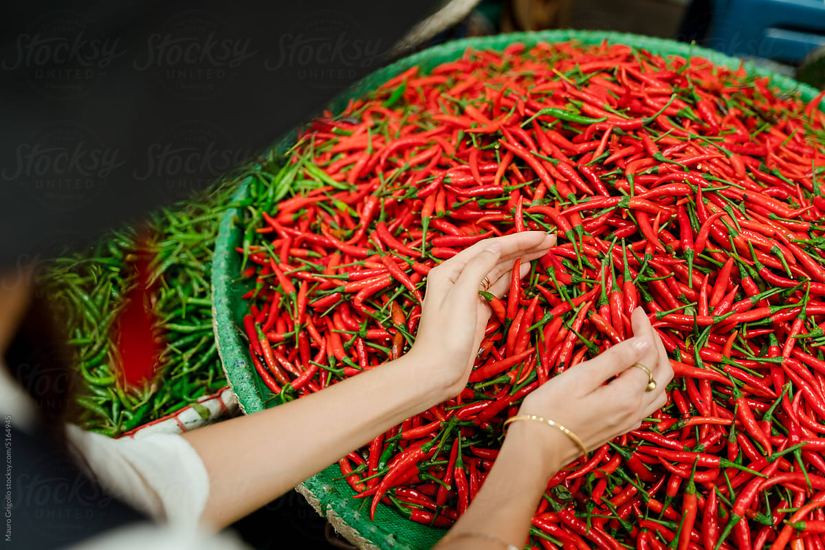 Anonymous woman looking at chili peppers at the market
