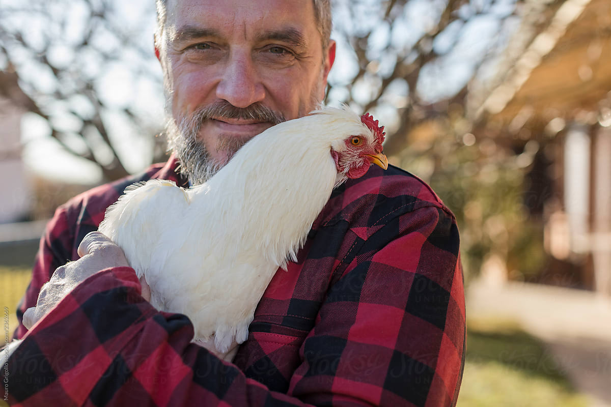 Man with a white hen in his arms
