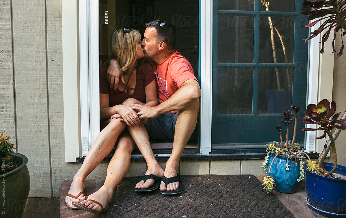 Married Middle Aged Couple Sitting In The Doorway Kissing By Stocksy Contributor Carolyn 