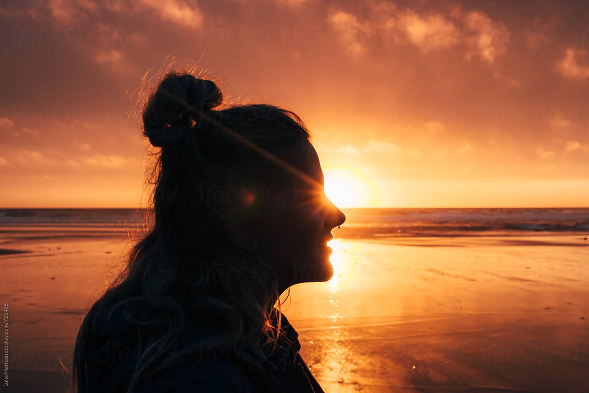 Profile Of A Young Woman\'s Face At Sunset On The Ocean Shore As The Sun Shines By Her Eyes