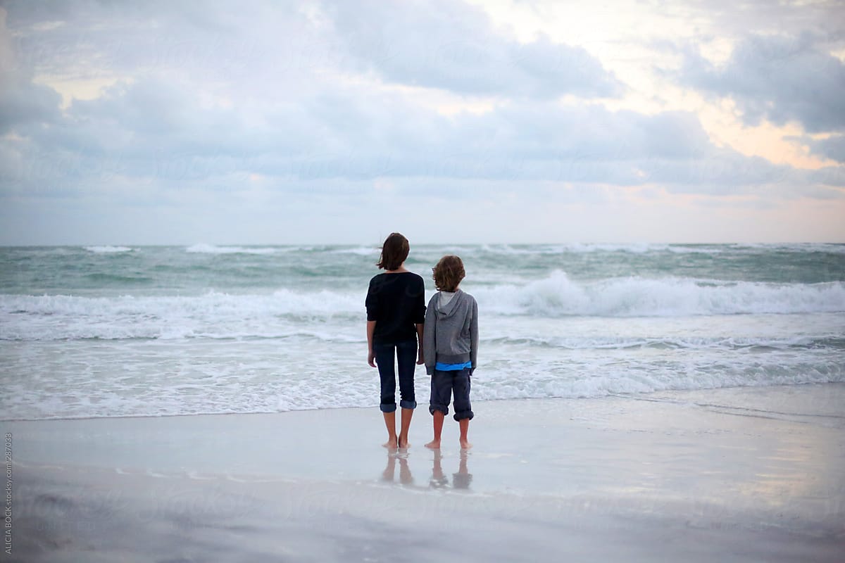 Siblings Standing On A Stormy Beach Watching Waves