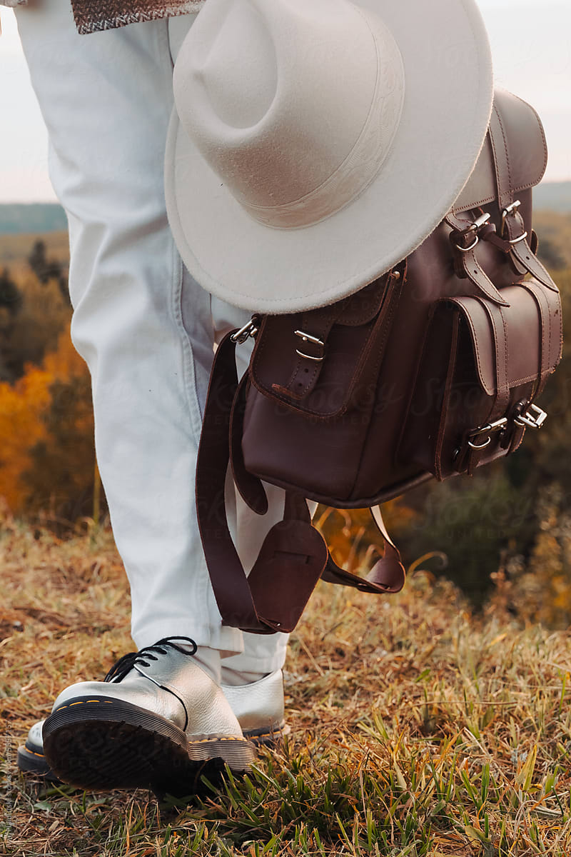 Stylish legs in silver shoes, hipster backpack, and cowboy hat in fall