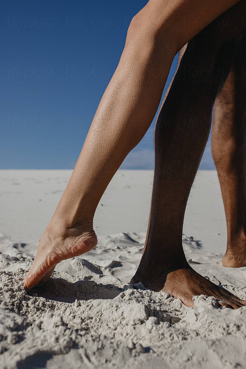 Legs of white woman and black man on the beach