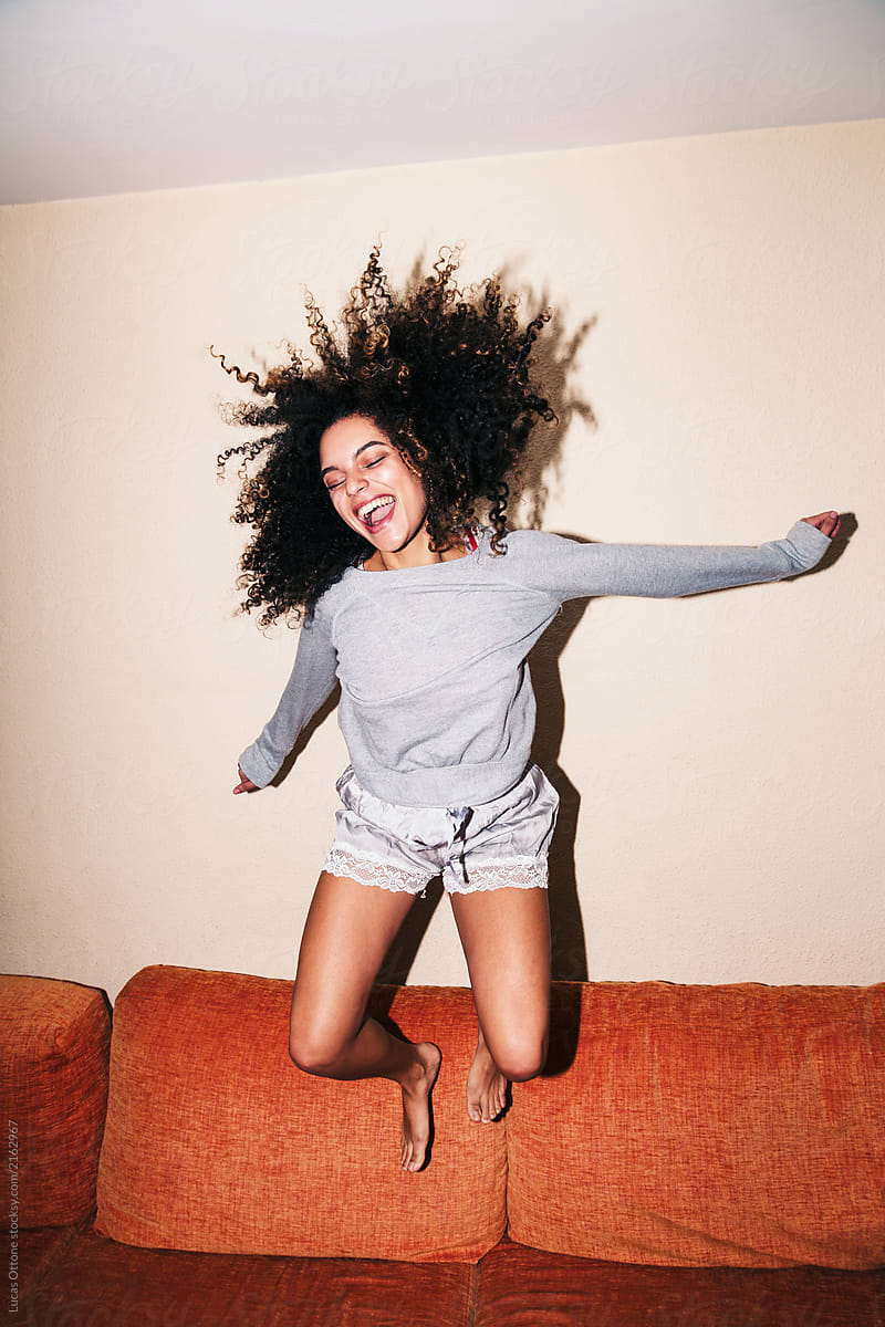 Happy afro woman jumping on the sofa