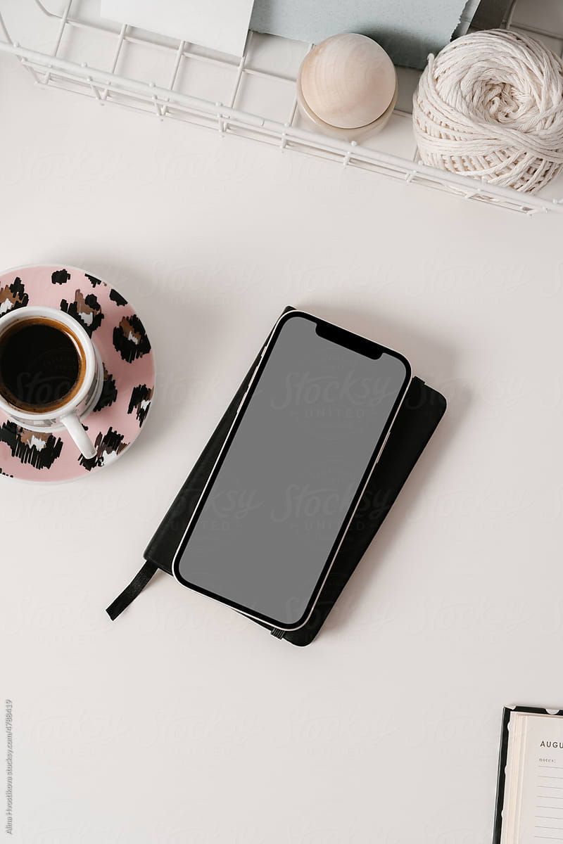 Smartphone with planner and coffee cup placed on desk