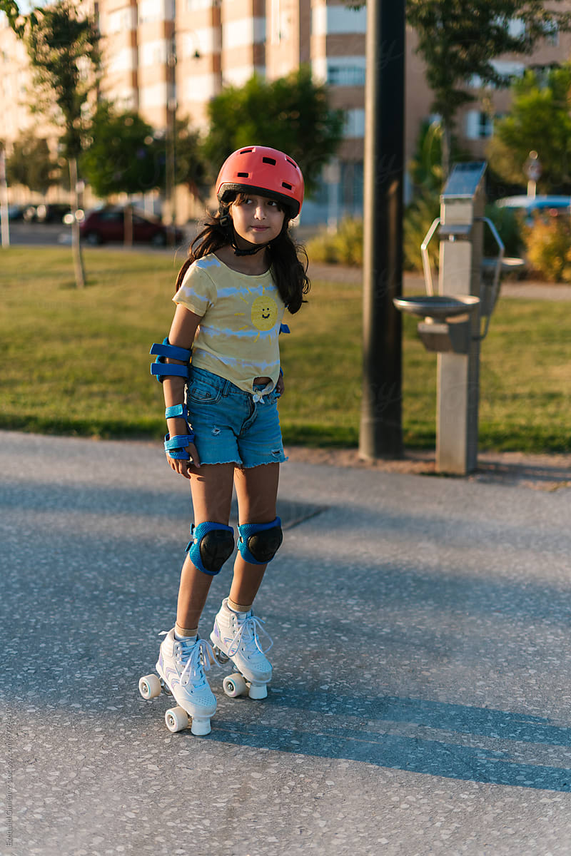 Little sportive girl riding roller skates on street