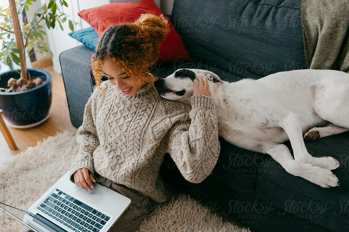 Happy teenager with computer stroking her lazy dog