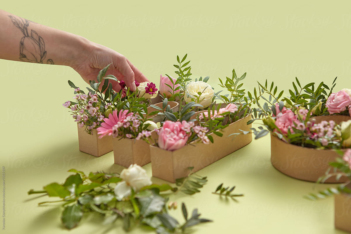 Flowers arranged by woman into paper craft boxes.