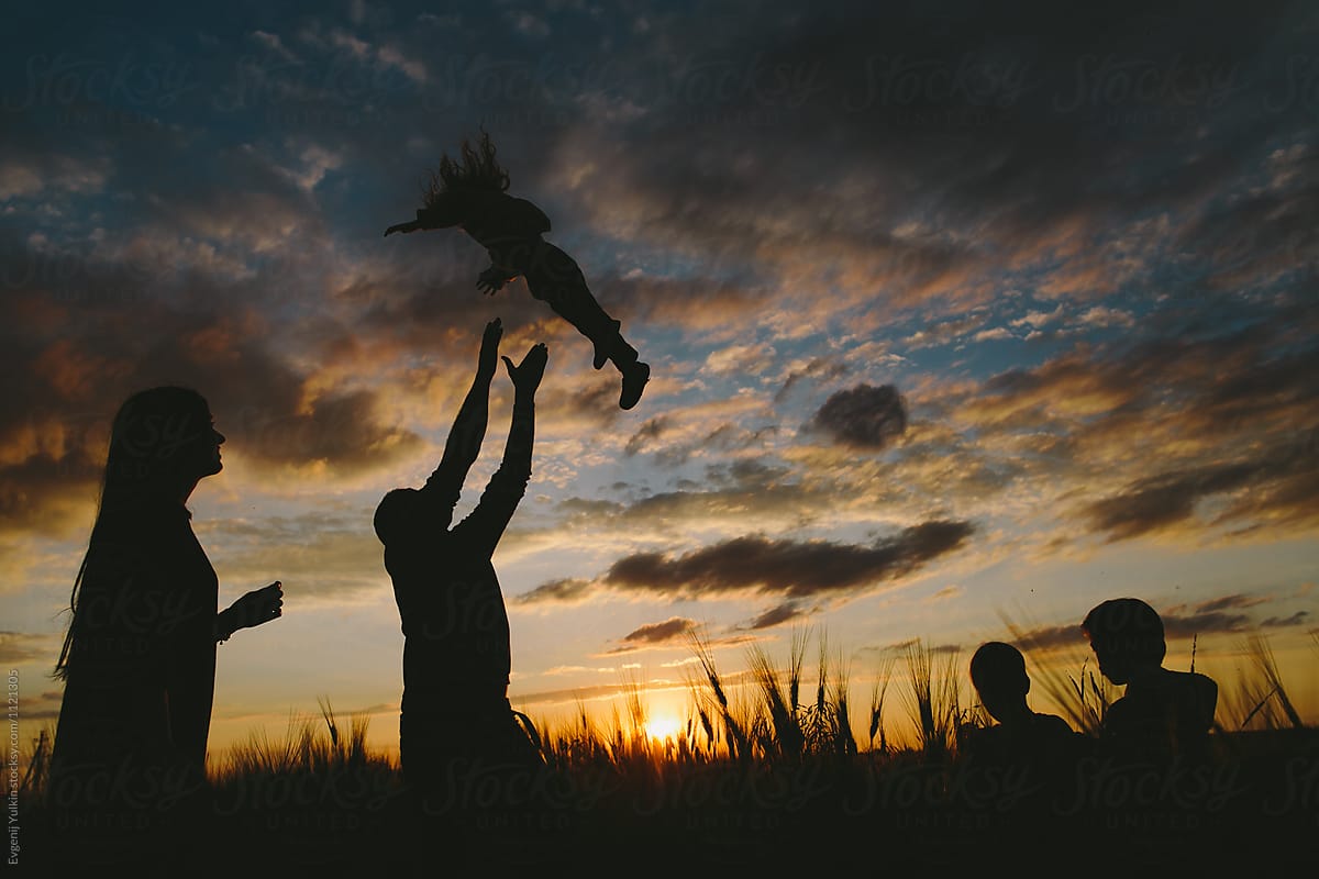 Silhouettes of family on open air at sunset