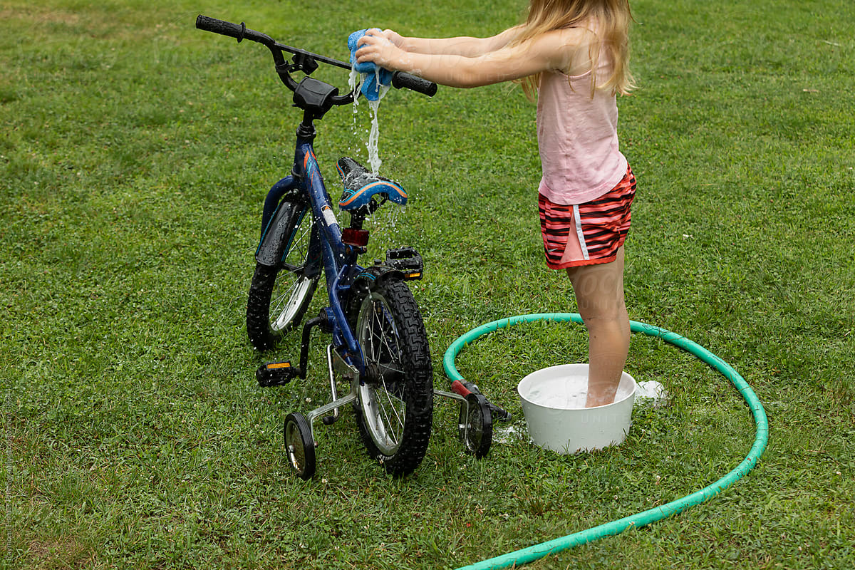 Young girl Washing her bicycle in the backyard of home