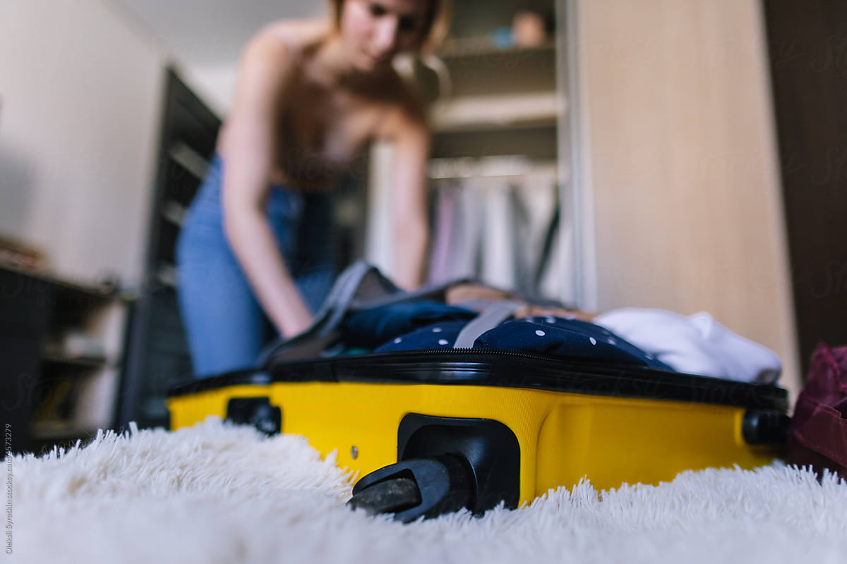 Female tourist putting in order clothes in suitcase