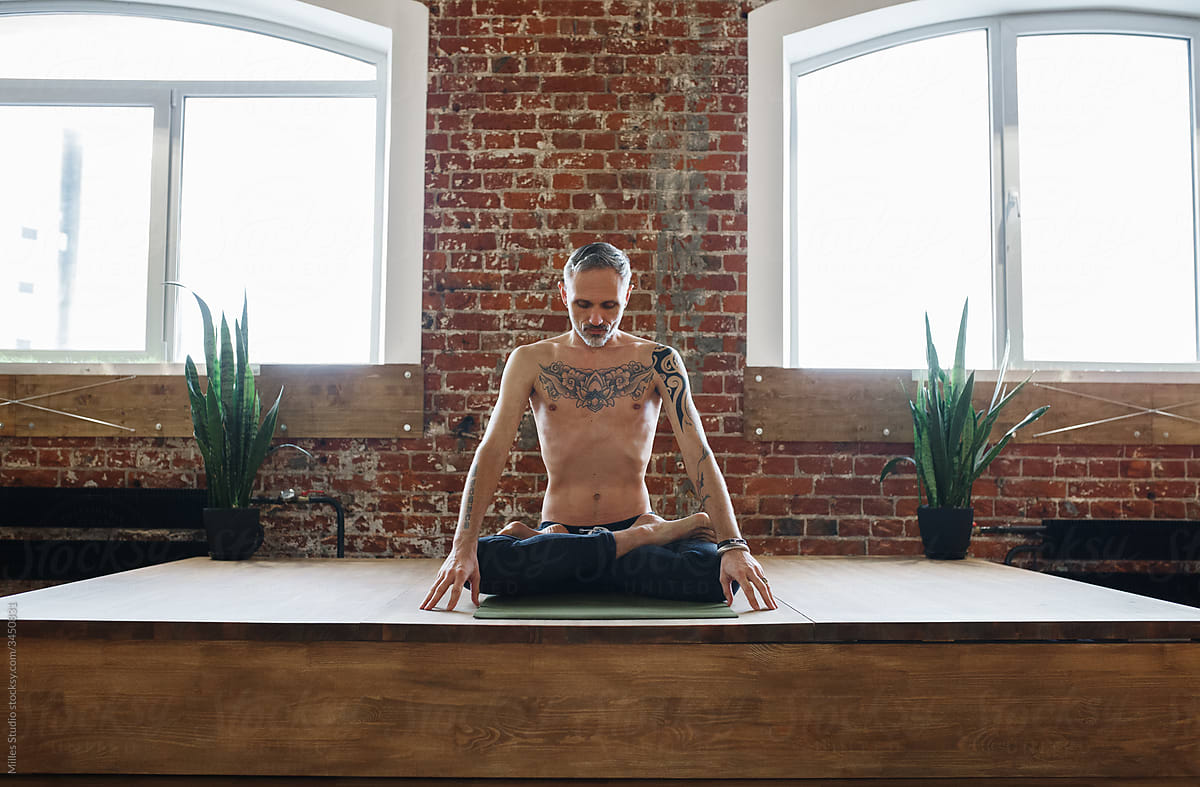 Tattooed man meditating in Lotus pose