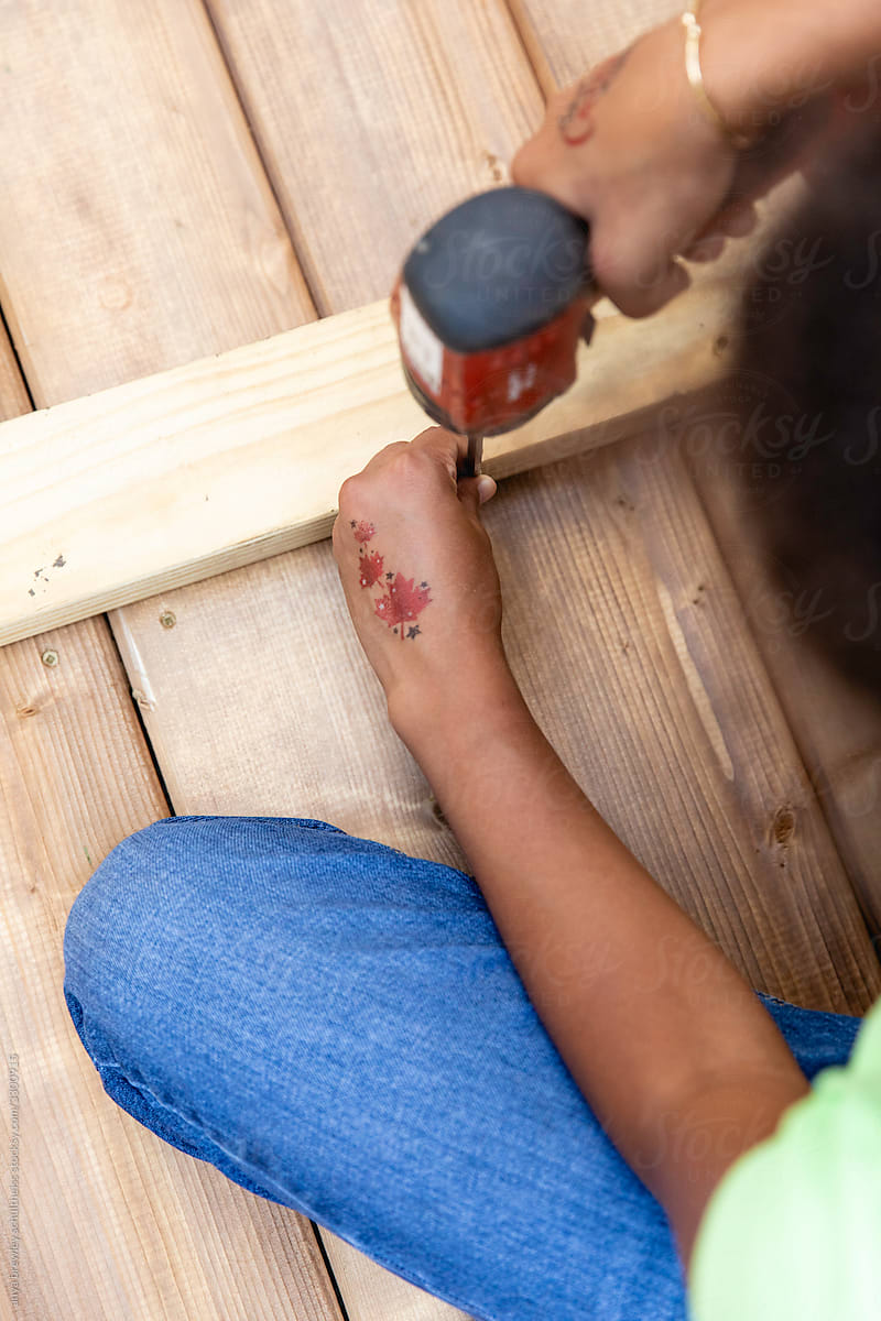 Tween girl  using power tools to help build a deck