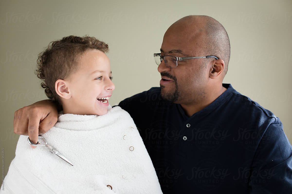 Laughing boy with father during haircut