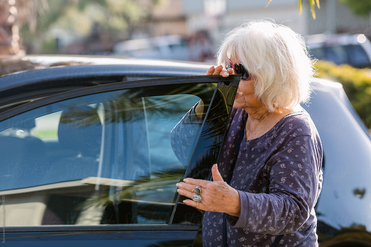 Mature modern woman opening car door at street