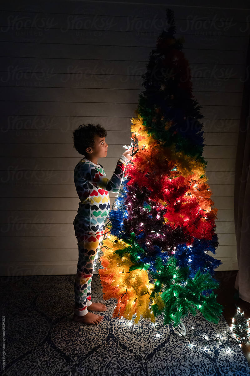 Girl adds lights to rainbow Christmas tree