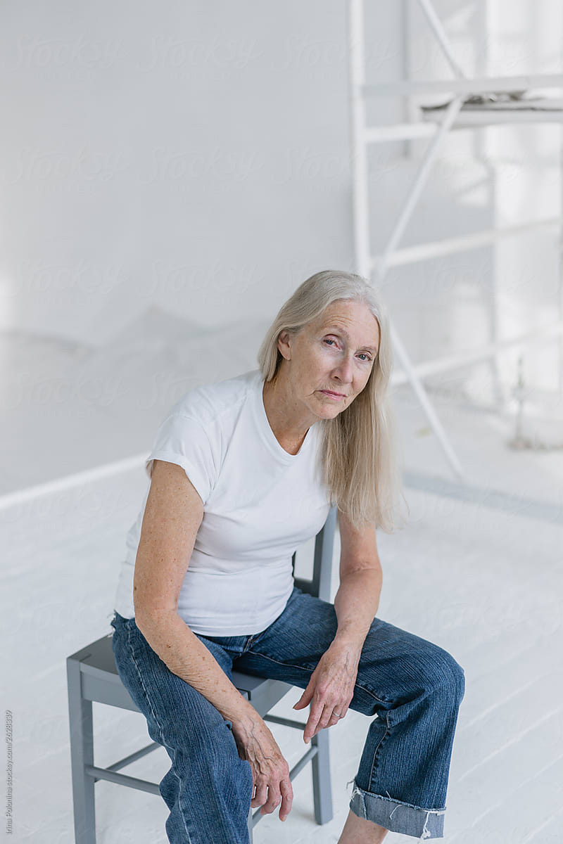 Portrait of a senior woman with grey long hair in white modern studio