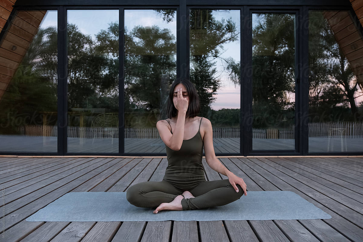 Female touching forehead and meditating on terrace