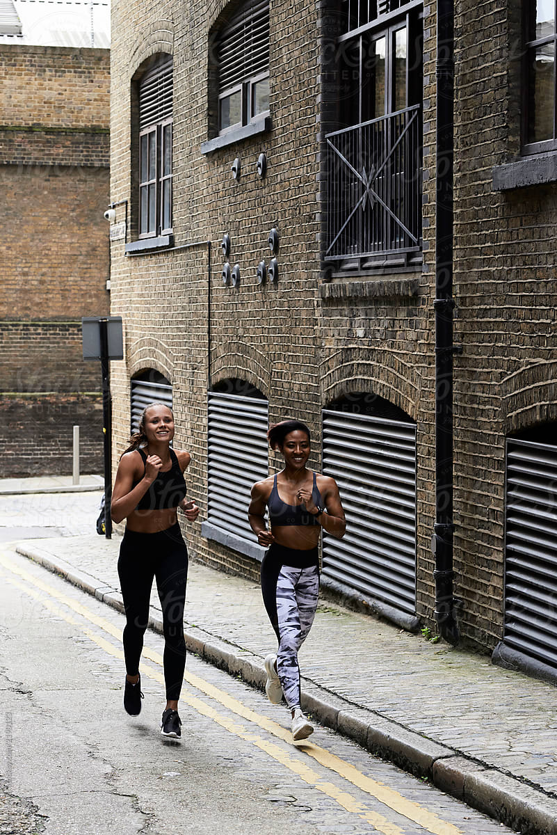 Sportswomen running during workout in urban street.