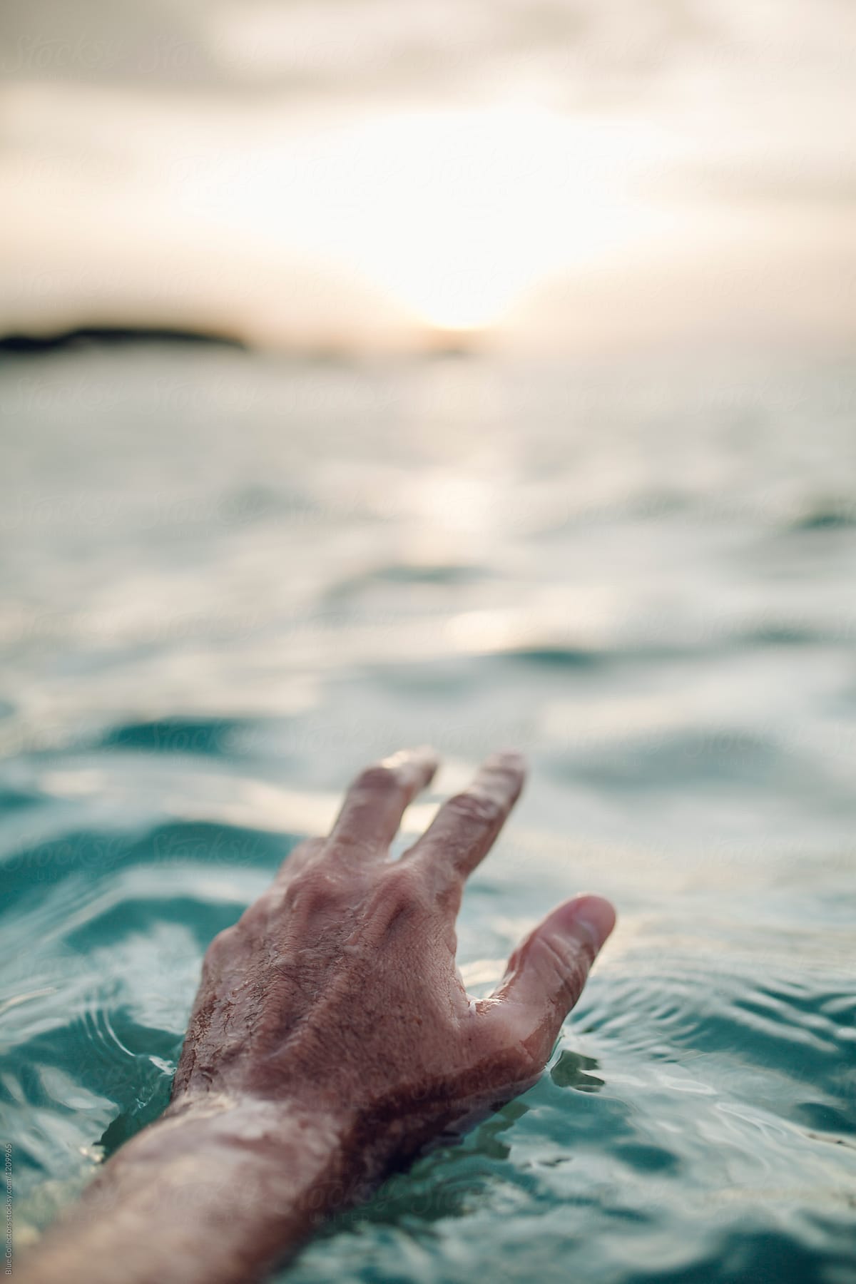 A man\'s hand on the seascape at sunset