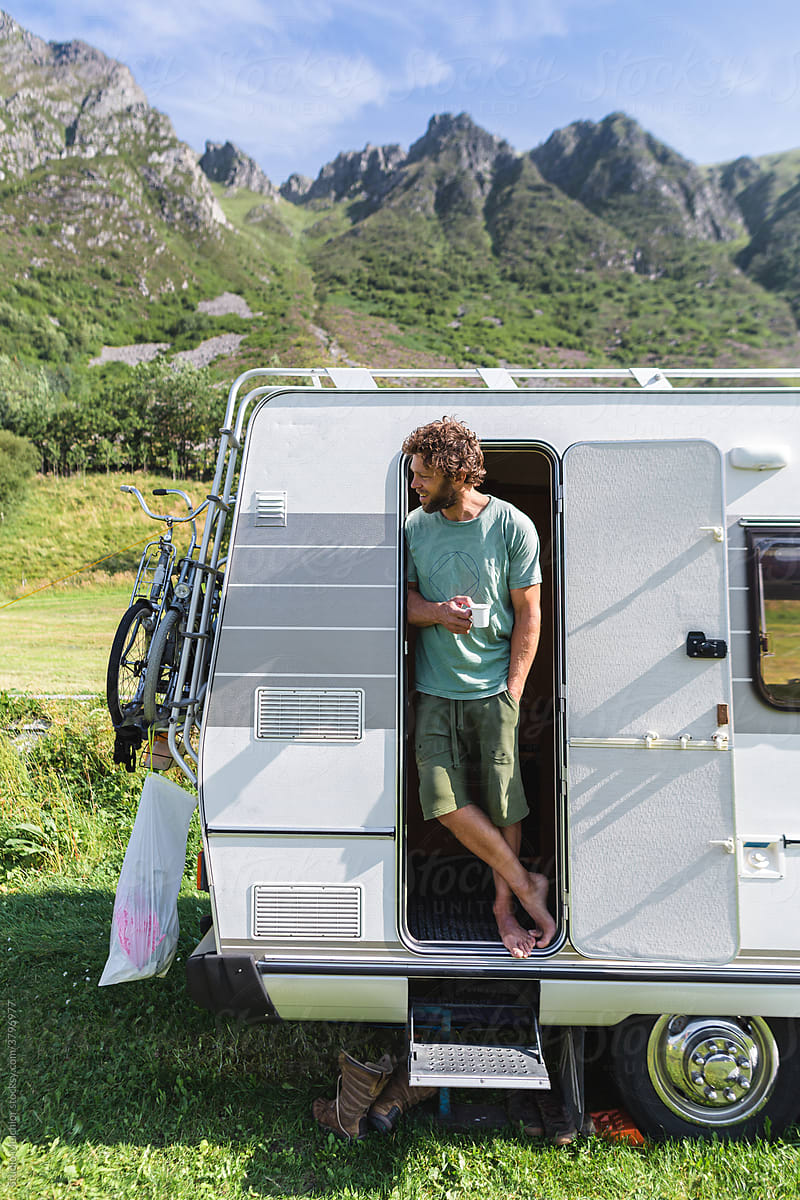 Young man drinking coffee in his campervan in the nature