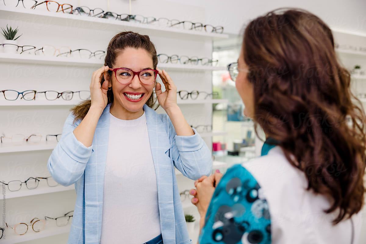 Cheerful woman picking eyeglasses with consultant