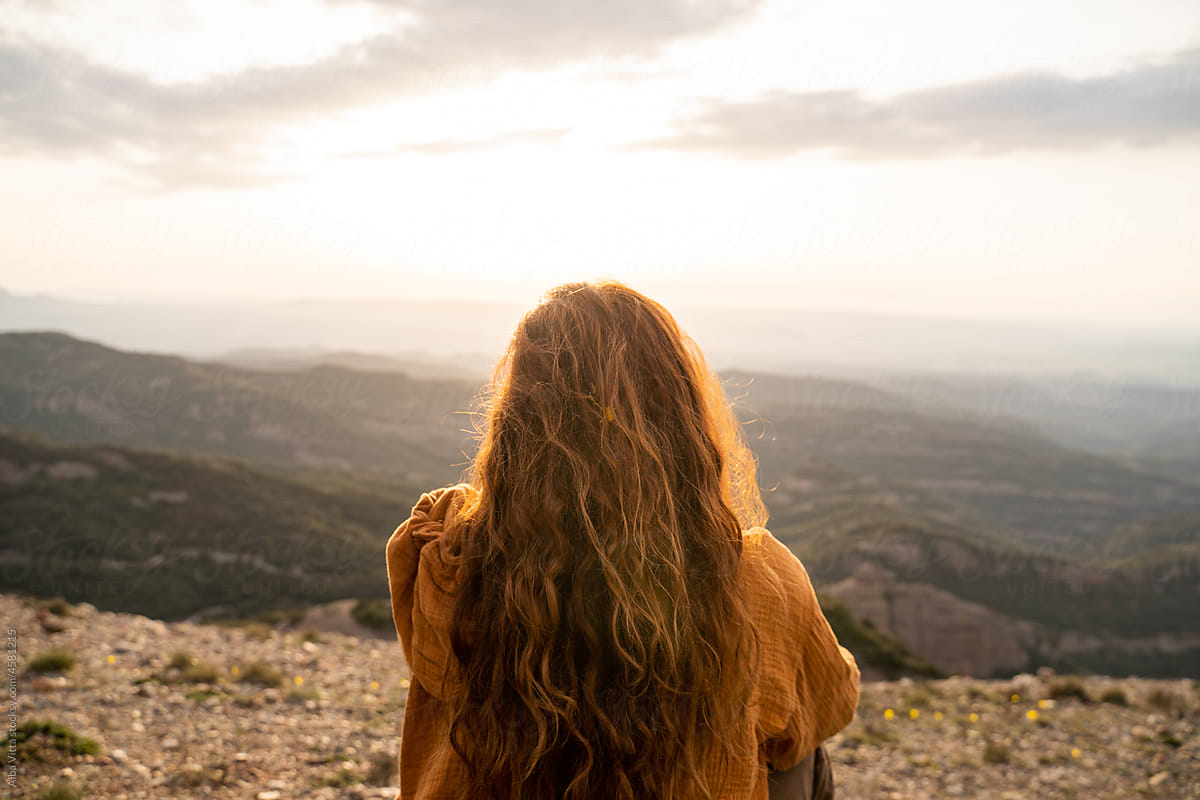 Back view of woman sitting in nature at sunset