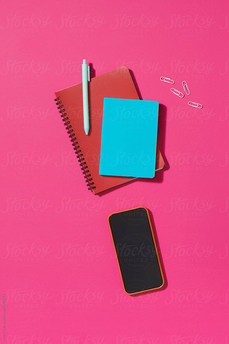 Notepad, smartphone, pen and sticky note on color table