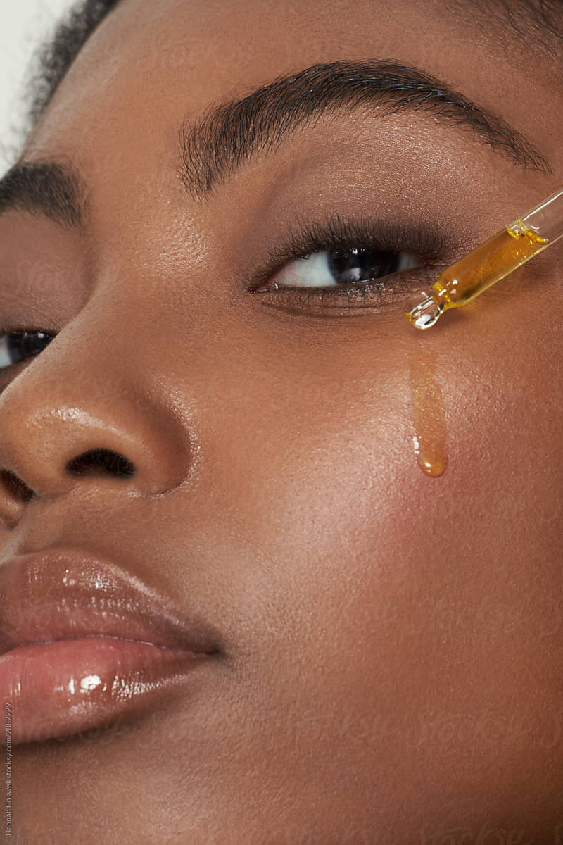 Model with face serum dripping on face