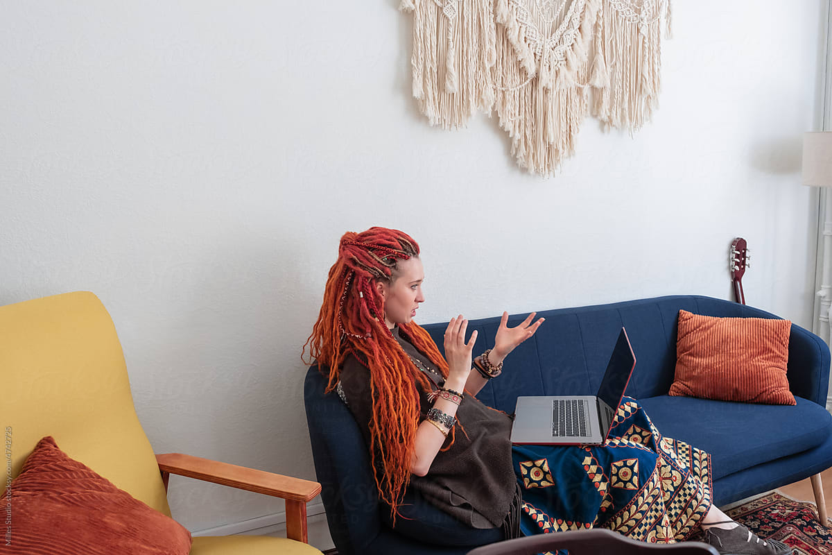Female hippie making video call on sofa