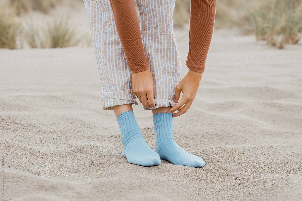 Trendy Young woman in fun blue socks standing in a sandy environment