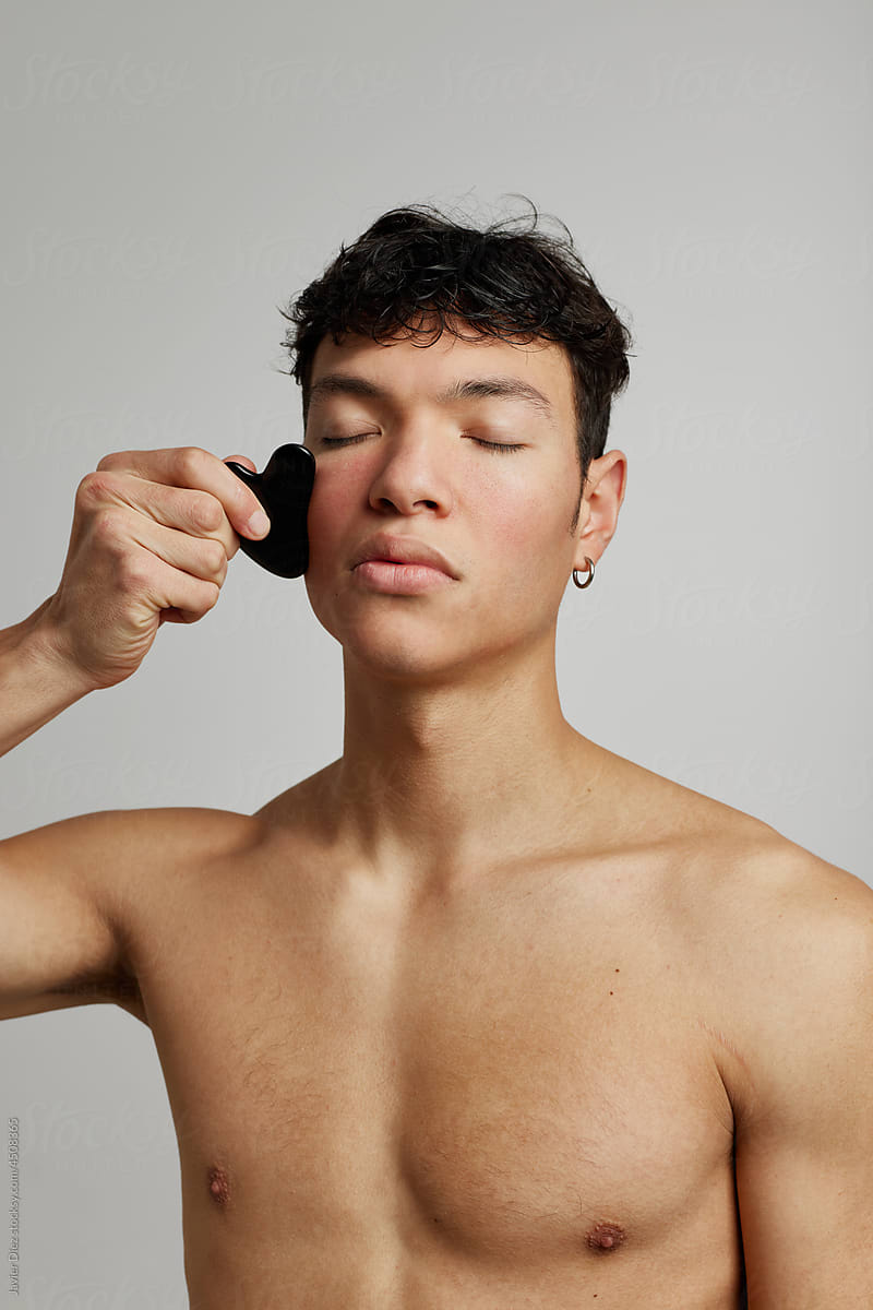 Man massaging face with cosmetic stone